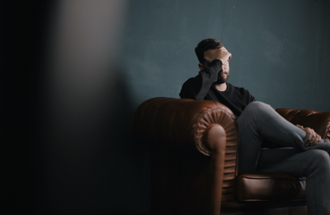 Man sitting on a couch thinking about why addicts keep relapsing.